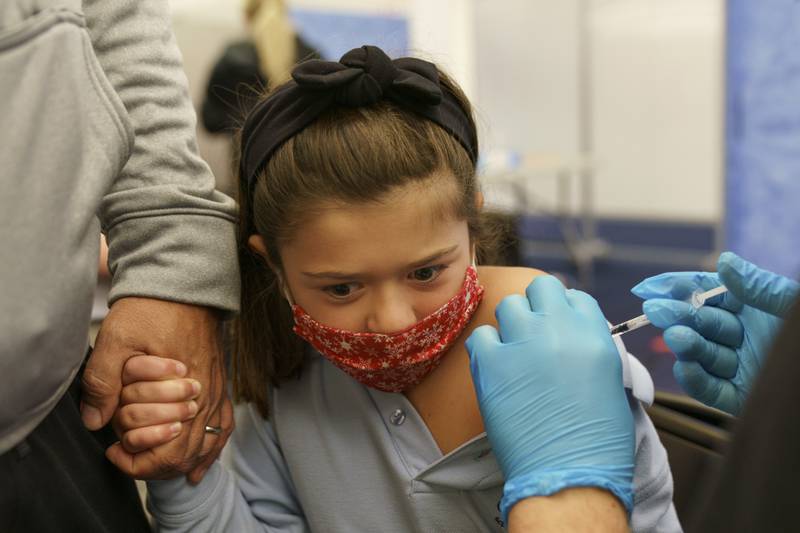 FILE - McKenzie Farias, 8, holds the hand of her father, Michael, as she receives the Pfizer COVID-19 vaccine for children ages 5-11 at a state-run site in Cranston, R.I., Nov. 4, 2021. As of Tuesday, Jan. 11, 2022, just over 17% of children in the U.S. ages 5 to 11 were fully vaccinated, more than two months after shots for them became available. (AP Photo/David Goldman, File)