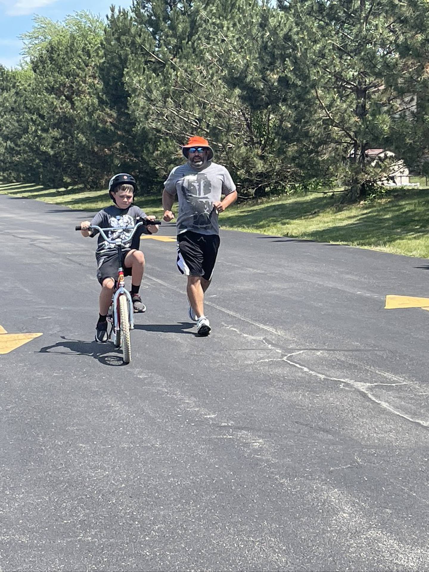 Noah Christie practices his biking skills with the help of supervisor Fred Manzi. 
The iCan Bike program, which teaches people with disabilities ages 8 and up to ride a conventional two-wheel bike, was June 14 to June 18, 2021, at Spencer Crossing School in New Lenox.