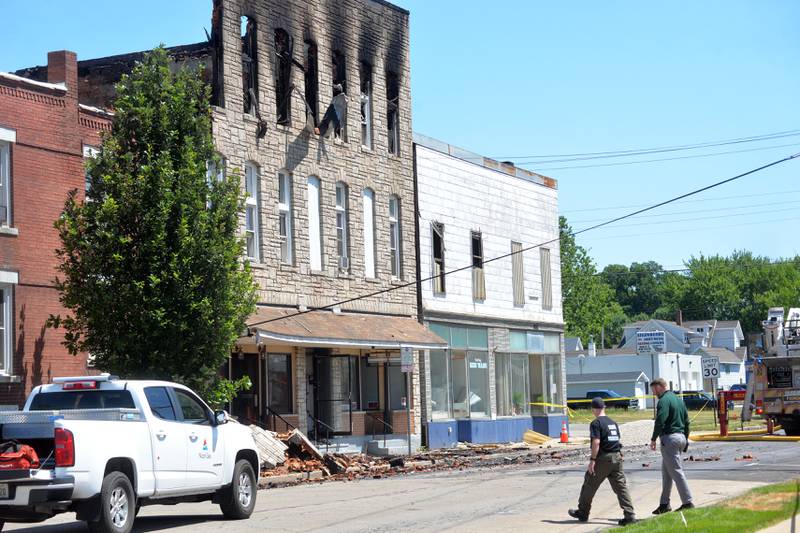 Two investigators walk across the street after an early morning fire at 406 East Third Street in Sterling destroyed a 3-story building.