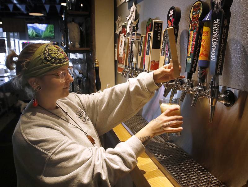 Abby Piluski pours a pint of Agrarian American Pale Ale, on Thursday, April 18, 2024, at Holzlager Brewing Company in Woodstock. The beer is of two beers brewed with hoops that McHenry County College grew last year.