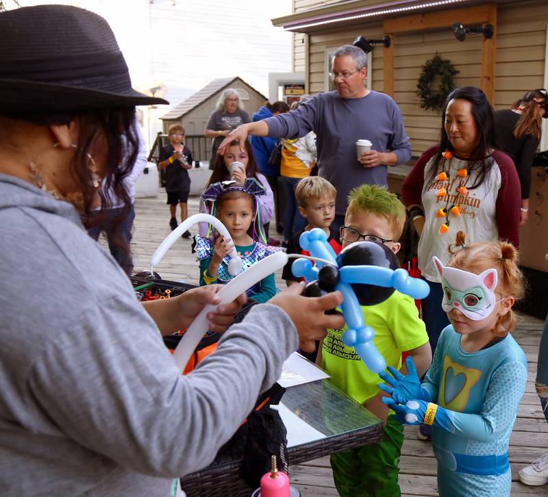 Sunny Knous (far right) watches as balloon artist Scarlett Diaz (left) makes a spider balloon for her at the Kamme-O-Circus Halloween Party on Saturday, Oct. 19, 2024 in Elburn.