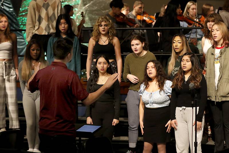Choir Director Brian Jozwiak leads the choir as they sing “Unknown” composed by Woodstock High School graduate Alex Riak on Thursday, Dec. 7, 2023, during a rehearsal for the school's “Across the Universe” concert.