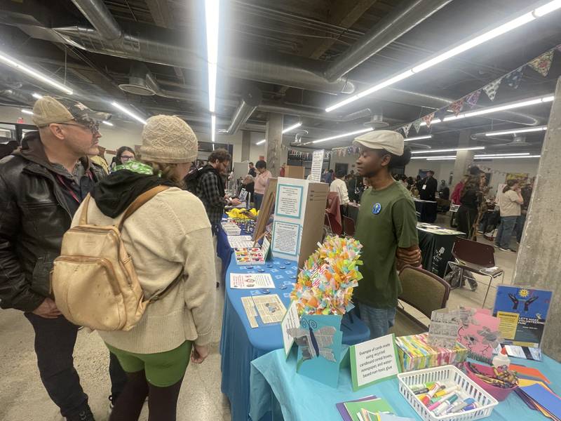 Mark Mattson (left) and Lynn Batalden are greeted by  Jordyn Jackson (right) of JOY Volunteers Saturday, April 11, 2026, at the annual DeKalb County Earth Fest held in NIU's Founders Memorial Library in DeKalb.