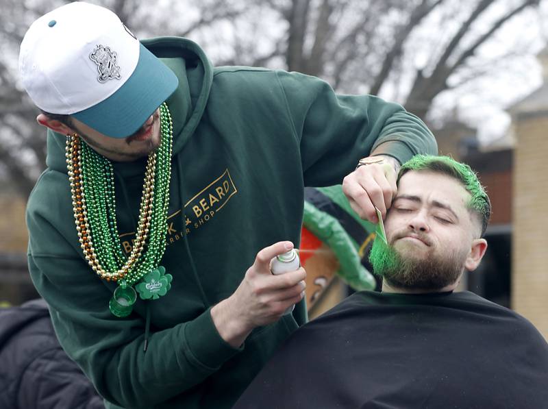 Dylan Stangeland dolors Jeff Begg’s beard as they ride on the Brook & Beard Barber Shop float during the McHenry ShamROCKS the Fox Festival Parade on Saturday, March 14, 2026. In McHenry.