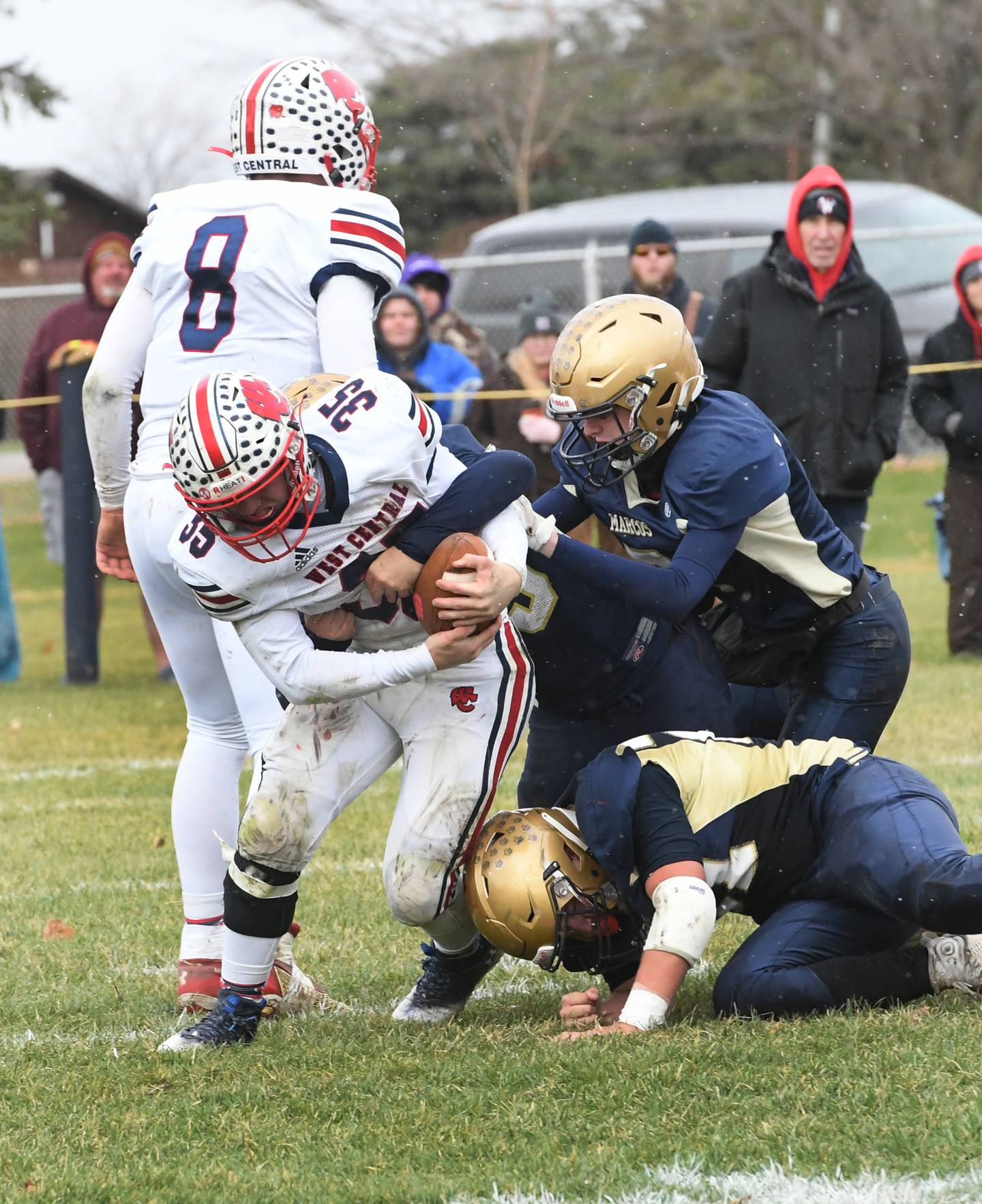 West Central's Parker Meldrom hangs onto to the ball as three Polo defenders tackle him during 8-man playoff action against Polo on Saturday, Nov. 12 in Polo.