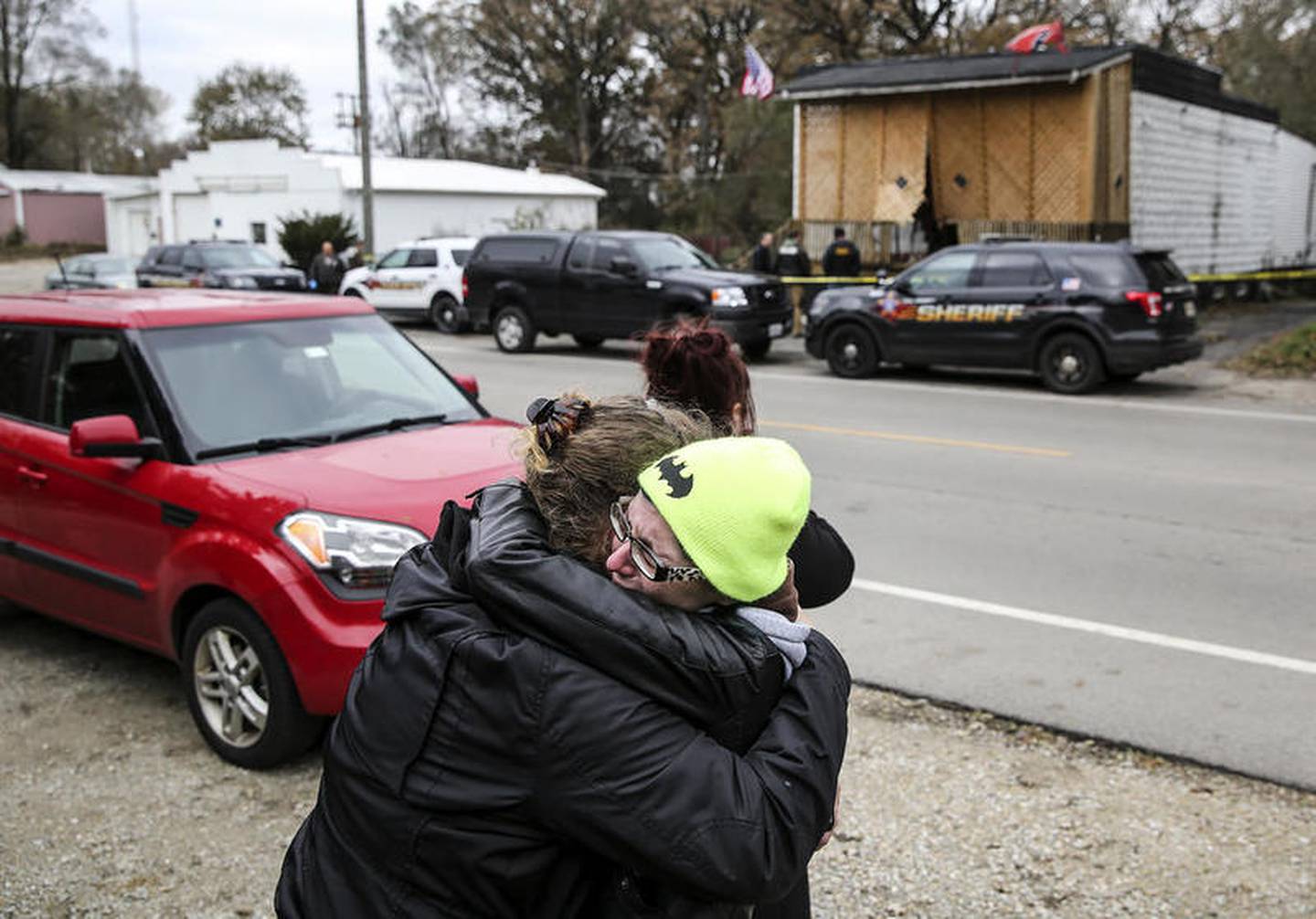 Marie Roche (right) and friends of Kaitlyn Kearns, a 24-year-old bartender from Joliet, hug each other Thursday, Nov. 16, 2017, along East Washington Street as county investigators search the clubhouse belonging to the Outlaws in Joliet, Ill. Kearns' body was found Thursday in a rural area of Kankakee County, according to a sheriff’s office news release.