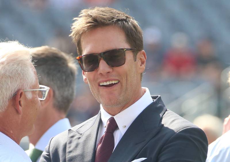 Former NFL player Tom Brady smiles while walking on the field before the game between the Chicago Bears and Dallas Cowboys on Sunday, Sept. 21, 2025 at Soldier Field.