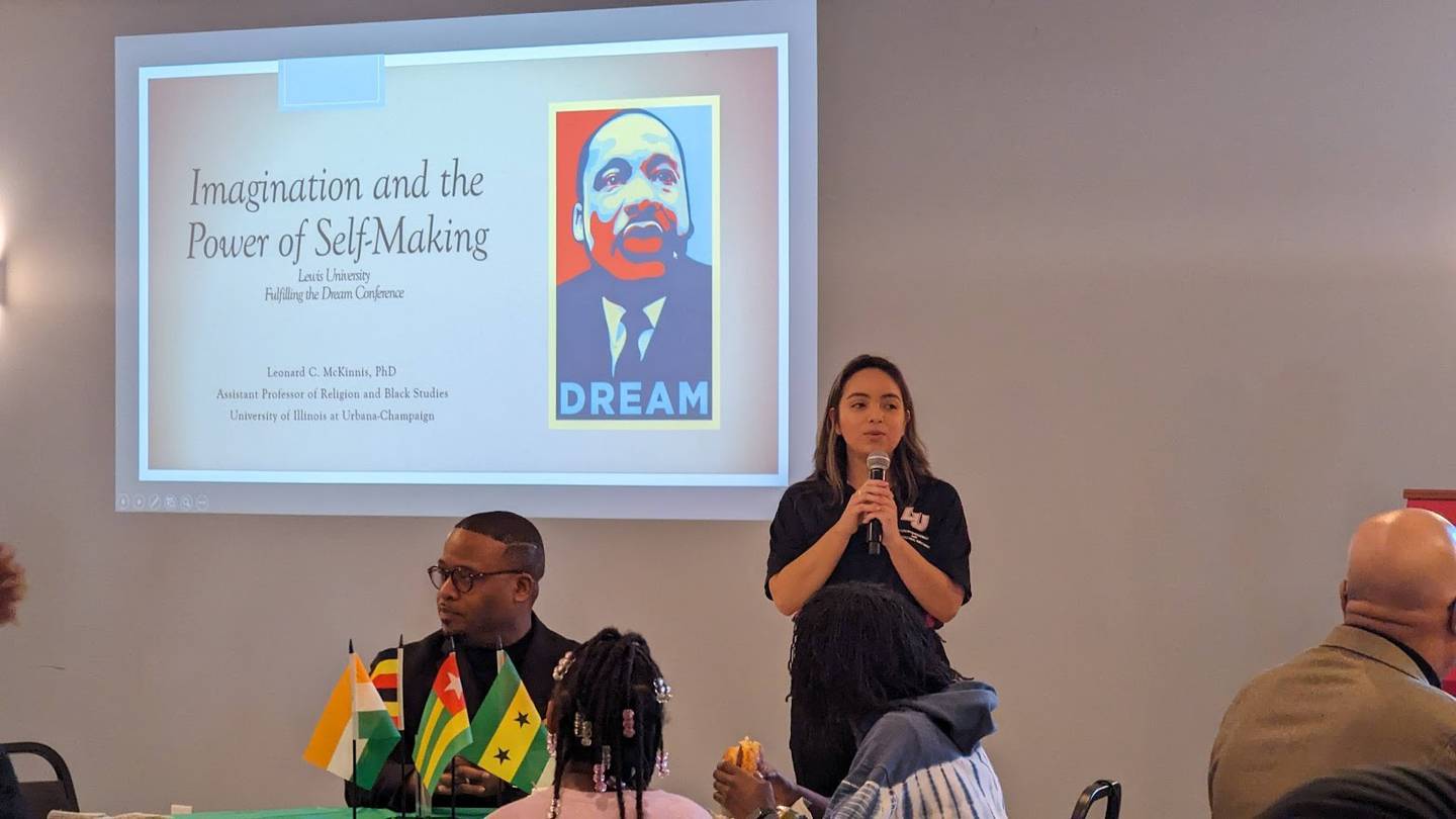 Diana Roman (right), coordinator for Student & Multicultural Engagement at Lewis University in Romeoville, introduces Lewis University alumna and author Leonard McKinnis (seated, left), assistant professor of African American Religions and Black Studies at the University of Illinois at Urbana-Champaign, at Lewis University's "Fulfilling the Dream" conference on Saturday, Feb. 17, 2024.