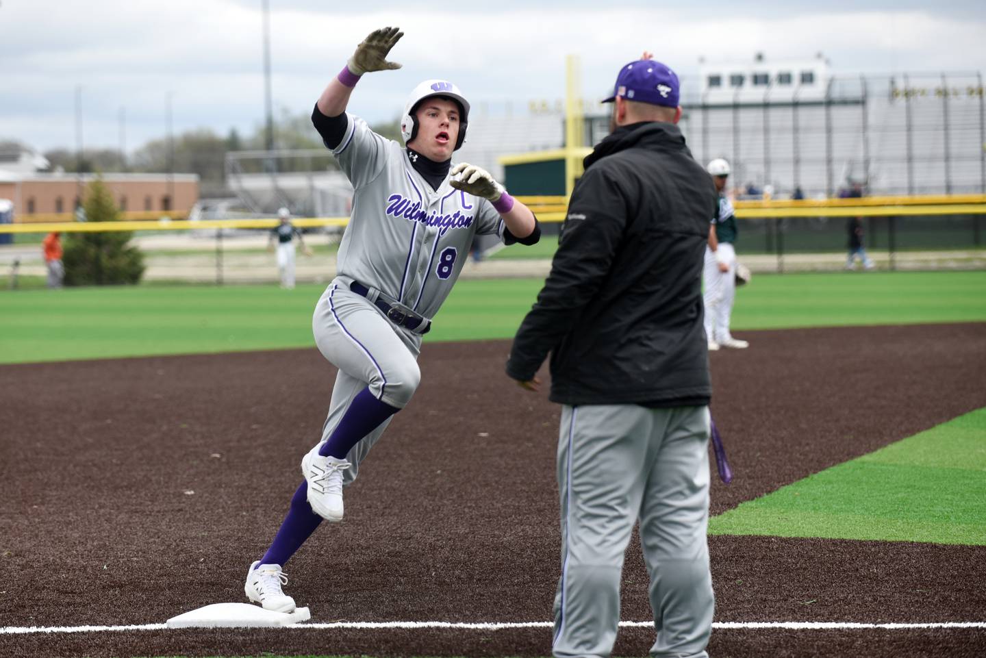 Wilmington's Kyle Farrell, left, high-fives head coach Mike Bushnell as he rounds third base to score on a home run during a game at Coal City Monday, April 21, 2025.