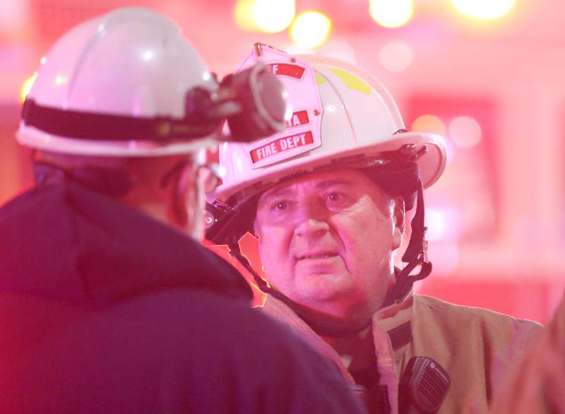 Mendota fire chief Dennis Rutishauser talks to an official from Nicor Gas while running the command post during a fire at 708 Illinois Avenue on Friday, Dec. 30, 2022 downtown Mendota.