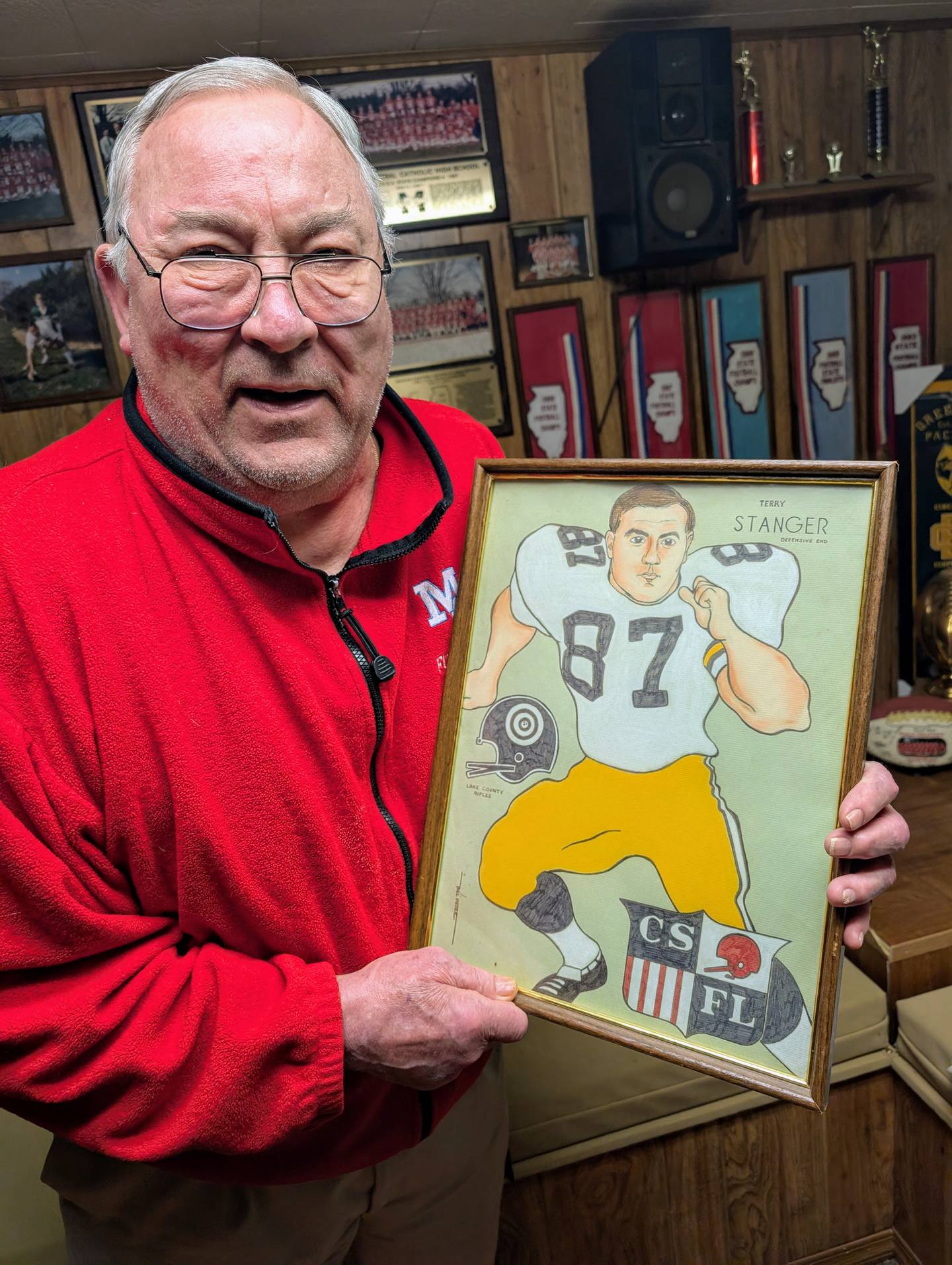Retired Marian Central football assistant coach Terry Stanger holds a framed caricature drawing of him when he played for the semi-pro Lake County Rifles, on Wednesday, Jan. 22, 2025, at his home in Woodstock.