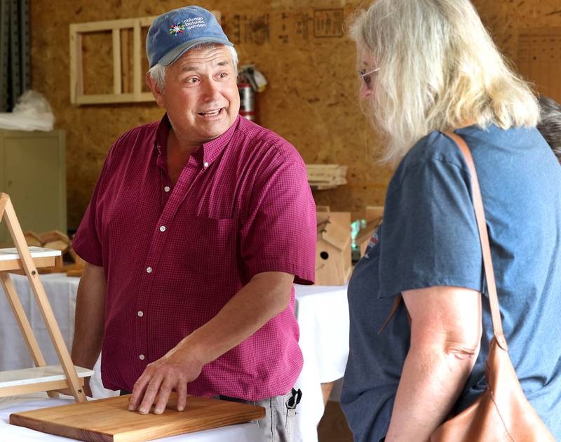 Dave Guss, from Sycamore, talks to a customer about some of his products at his D. Guss Crafts booth Tuesday, June 3, 2025, during the the Sycamore Farmers Market, hosted by Kar-Fre Flowers and Gifts. The market will be held Tuesdays from 3-6 p.m. through August 26 at Kar-Fre Flowers. Some of the market was held indoors due to the weather.