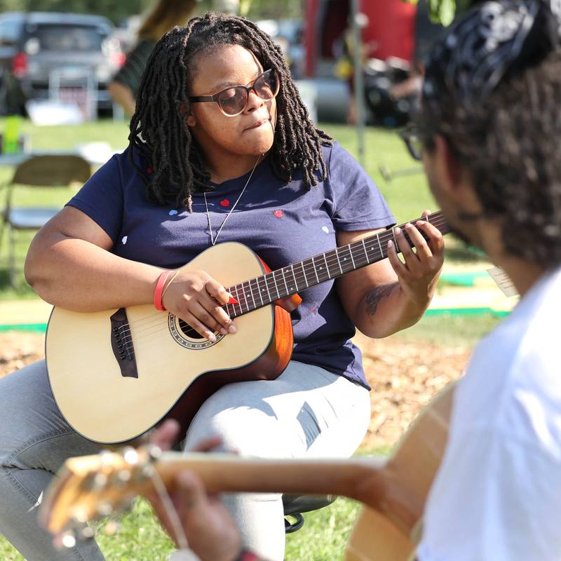 Javier Sanchez, (right) with Aurora Music Company, shows Adrianna Carr, from Chicago some chords during the Family Fun Fest Thursday, July 20, 2023, at Hopkins Park in DeKalb.