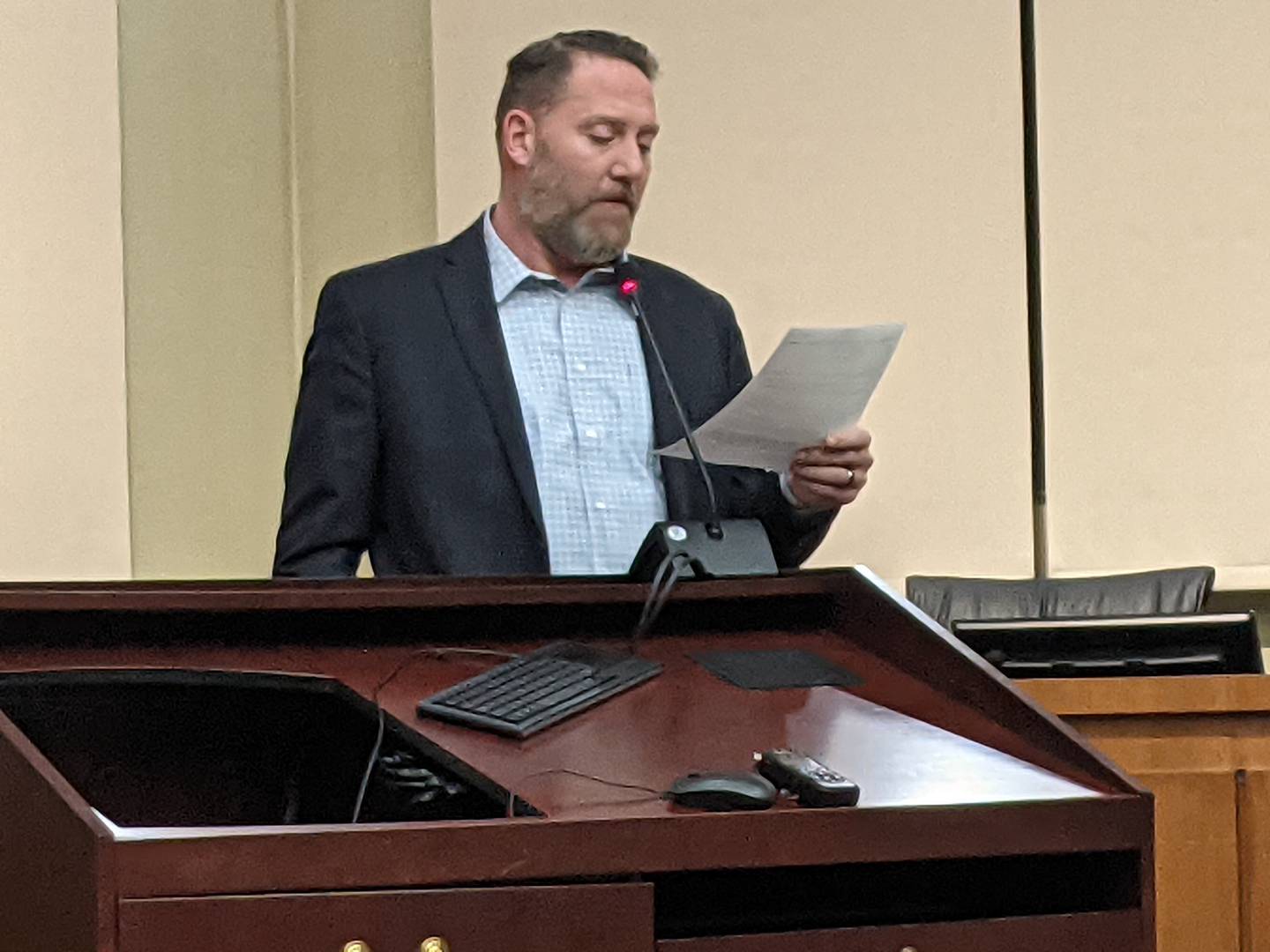 Oswego Area Chamber of Commerce Board Chairman Rick Warner reads a statement from Oswego Village Board candidate James Marter II during a March 3 candidate forum hosted by the Oswego Area Chamber of Commerce.