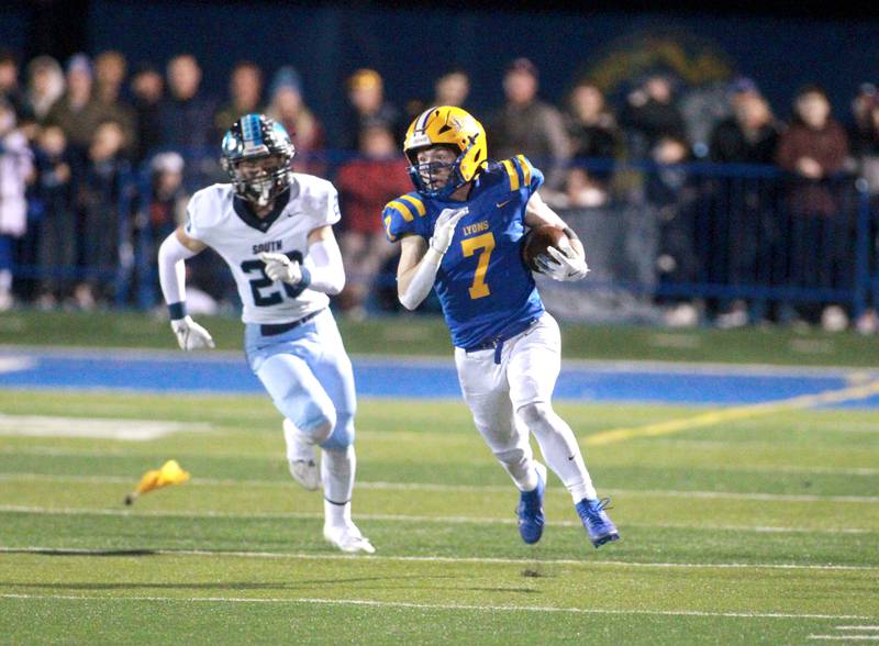 Lyons Township’s Danny Carroll runs with the ball as he’s chased down by Downers Grove South’s Coen Godenschwager and there’s a flag on the play during the Class 8A second-round game on Friday, Nov. 8, 2024 at Lyons Township in Western Springs.