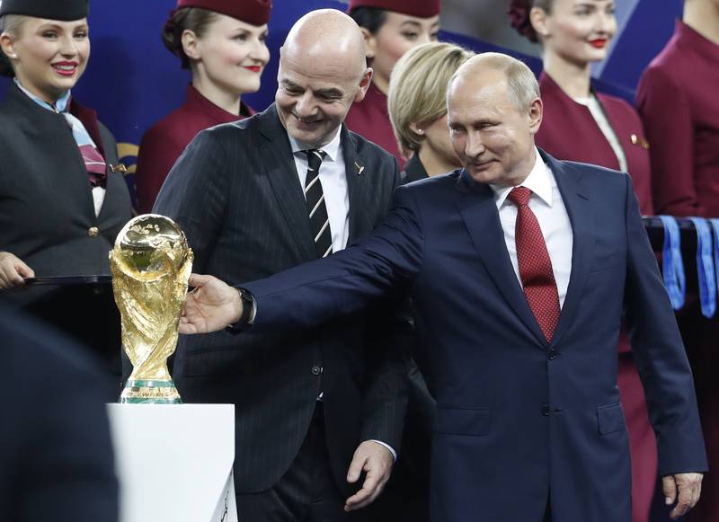 Russian President Vladimir Putin touches the World Cup trophy as FIFA President Gianni Infantino stands beside him, at the end of the final match between France and Croatia at the 2018 soccer World Cup in the Luzhniki Stadium in Moscow, Russia, Sunday, July 15, 2018. In a sweeping move to isolate and condemn Russia after invading Ukraine, the International Olympic Committee urged sports bodies on Monday to exclude the country's athletes and officials from international events. The decision opened the way for FIFA, the governing body of soccer, to exclude Russia from a World Cup qualifying playoff match on March 24. Poland has refused to play the scheduled game against Russia.