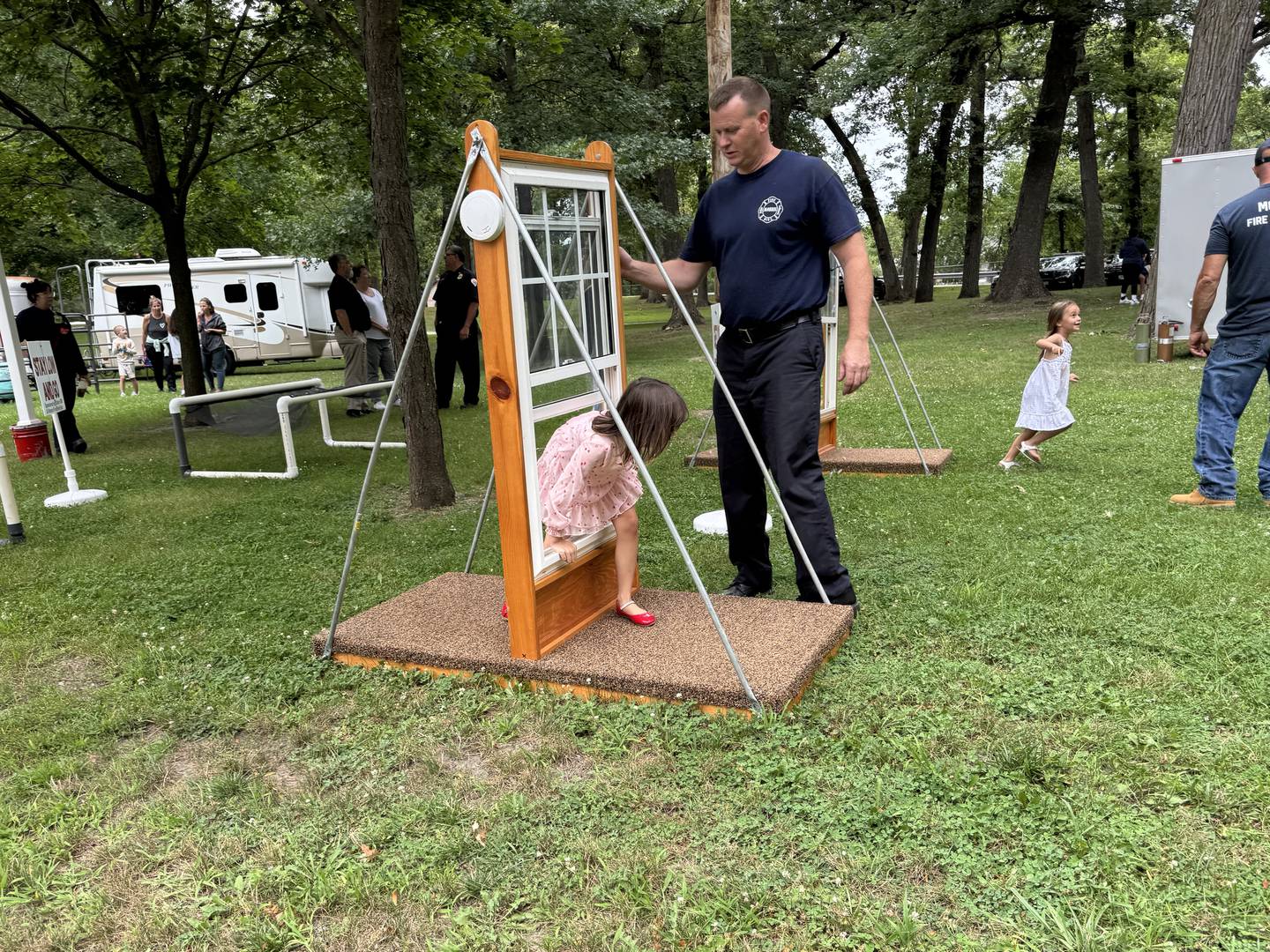A Morris Firefighter guides 6-year-old Maggie through an obstacle course designed to teach kids what to do in case of a fire.