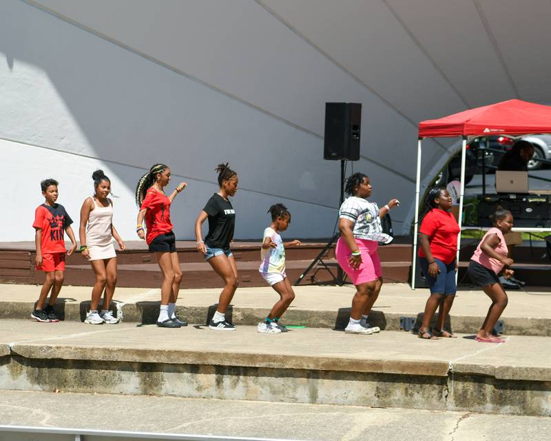 Children don't mind the head as they line dance together on Sunday, June 22, 2025, during DeKalb's annual Juneteenth Community Celebration held at Hopkins Park.