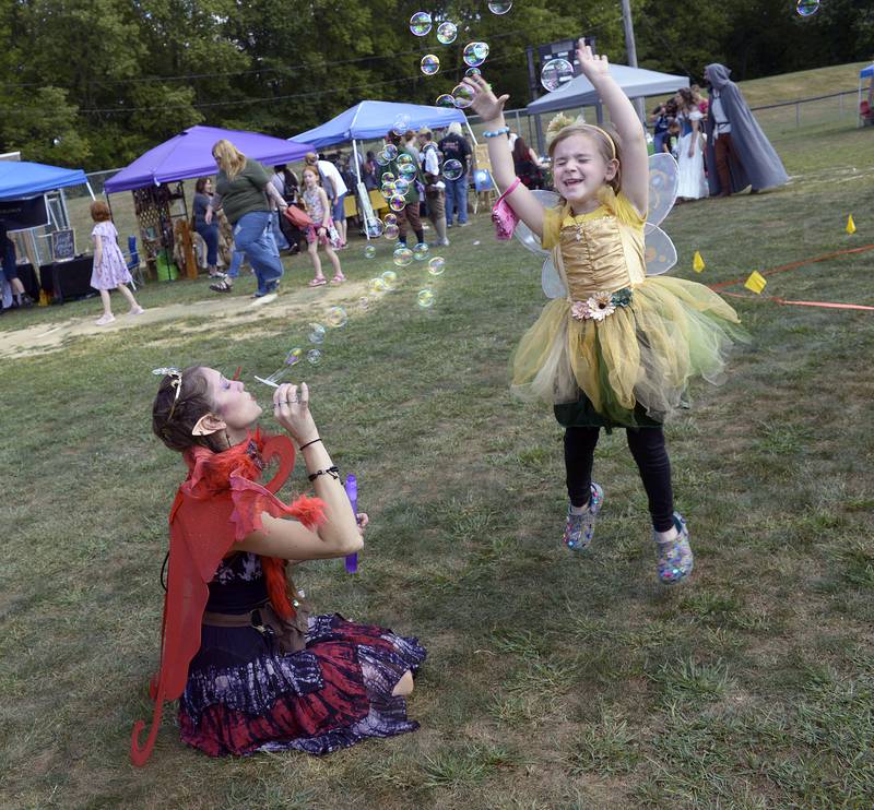 Hillary Anderson blows bubbles while Audi Reinhart dances among them Saturday during the annual Marseilles Renaissance Faire.