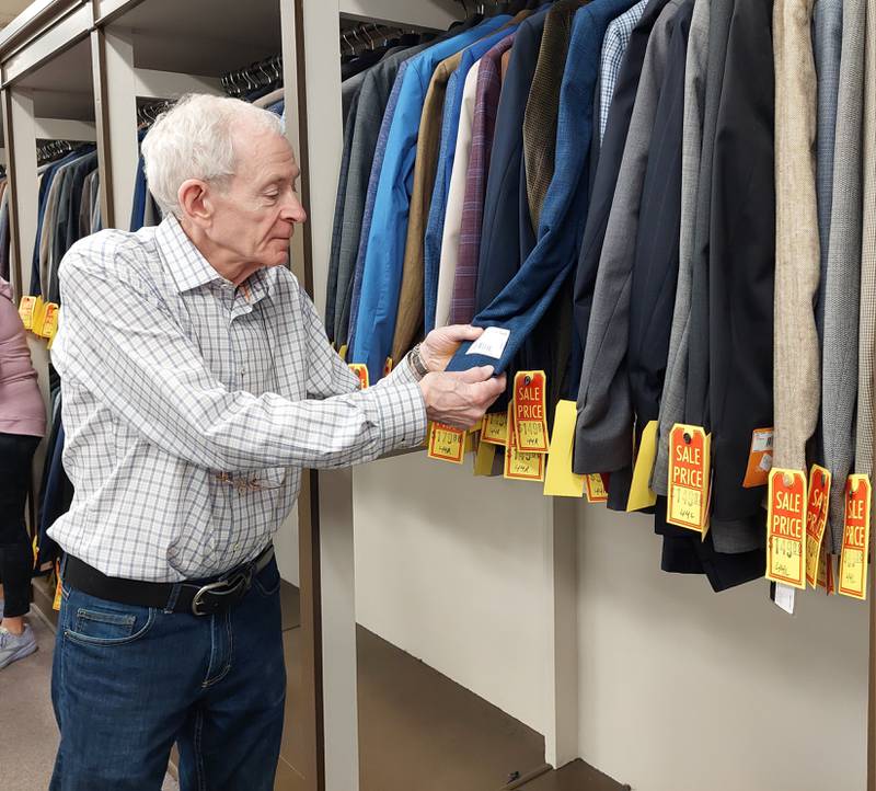 Patrick Graham displays a tag from one of the jackets on sale Tuesday, March 5, 2024, at I. Bell's Clothing store in downtown Ottawa. Graham is retiring after 45 years working at the men's store.