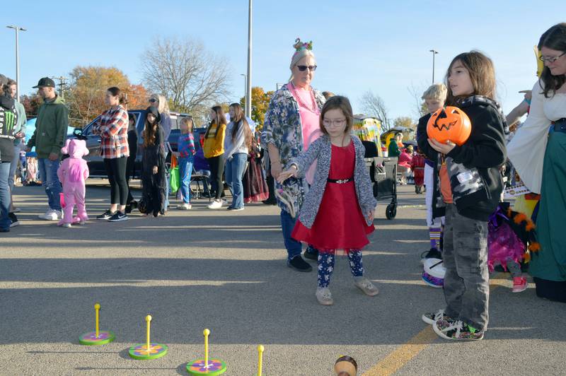 Auralia Trahan, 7, of Polo, throws a ring as part of a game while older brother James Trahan, 8, (right) watches on Saturday, Oct. 26, 2024, at a trunk-or-treat at Crossroads Community Church's Polo campus.