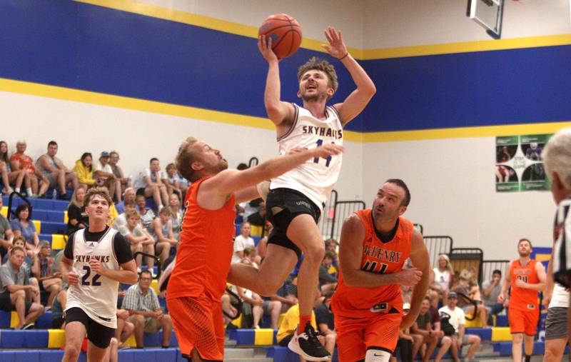 Johnsburg’s Zach Toussaint, center, soars as McHenry’s Ryan Skinner, left, and Jimmy Ernst defend during an alumni basketball game at Johnsburg High School Saturday evening to benefit the family of Jackson Werderitch, a 10-year-old who was struck by a car.