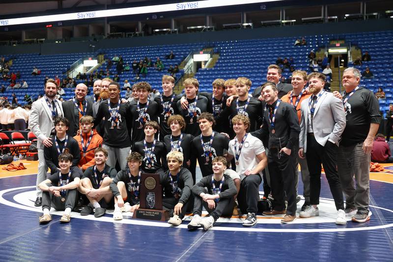 St. Charles East wrestlers and coaches pose with the IHSA Class 3A Dual Team State third place trophy following their victory over Oak Park-River Forest on Saturday, Feb. 28, 2026.