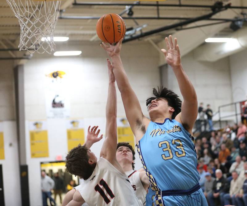 Marquette's Blayden Cassel lets go of a shot under the hoop over Woodland's Nate Berry during the Tri-County Conference Tournament championship on Friday, Jan. 30, 2026 at Putnam County High School.