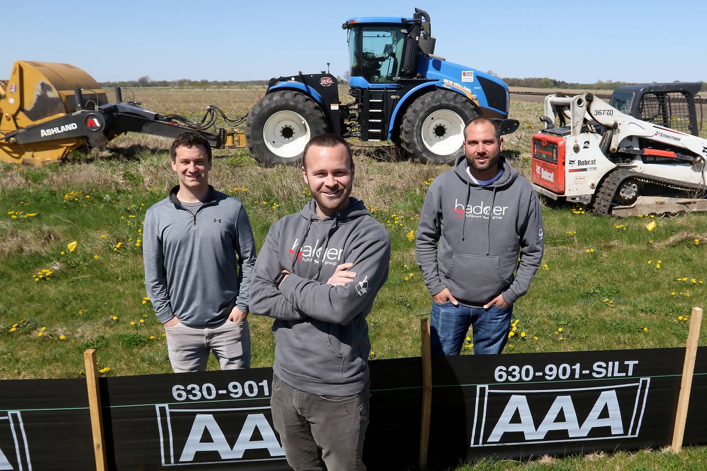 Badger Fulfillment Group President Kyle Kobriger, front, and parters Jared Kobriger, left, and Lance Wagner, right, pose for a photo Friday, April 30, 2021, with construction equipment being used to prepare the land on Commanche Circle for a new 120,000-square-foot facility in Harvard. The new building will also make way for about 10 new jobs and is expected to open around October.