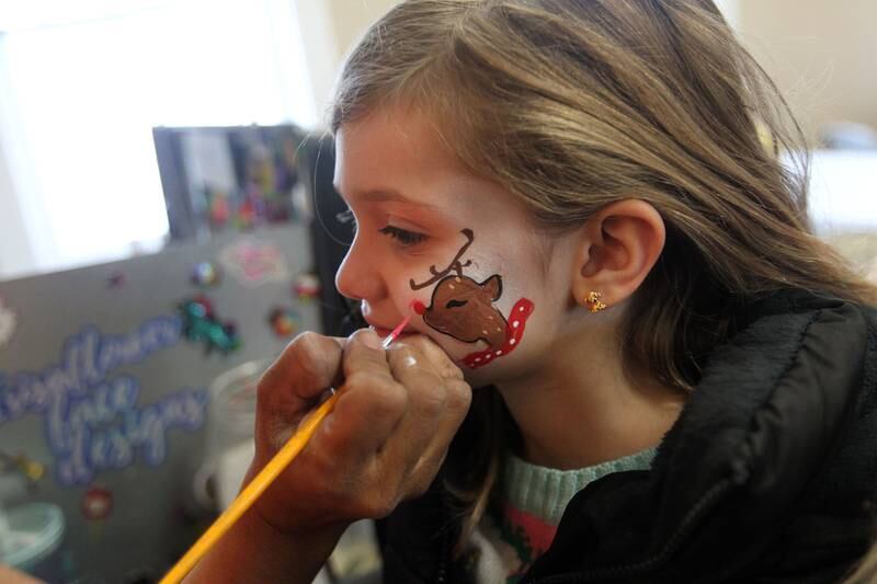 Candace H. Johnson for Shaw Local News Network
Iris Killian, face painter with Irisaflower Face Designs, paints a reindeer on Paisley Baryla, 5, both of Wauconda in the Community Room at the Wauconda Area Chamber of Commerce during Holiday Walk on Main in Wauconda.  (12/4/22)