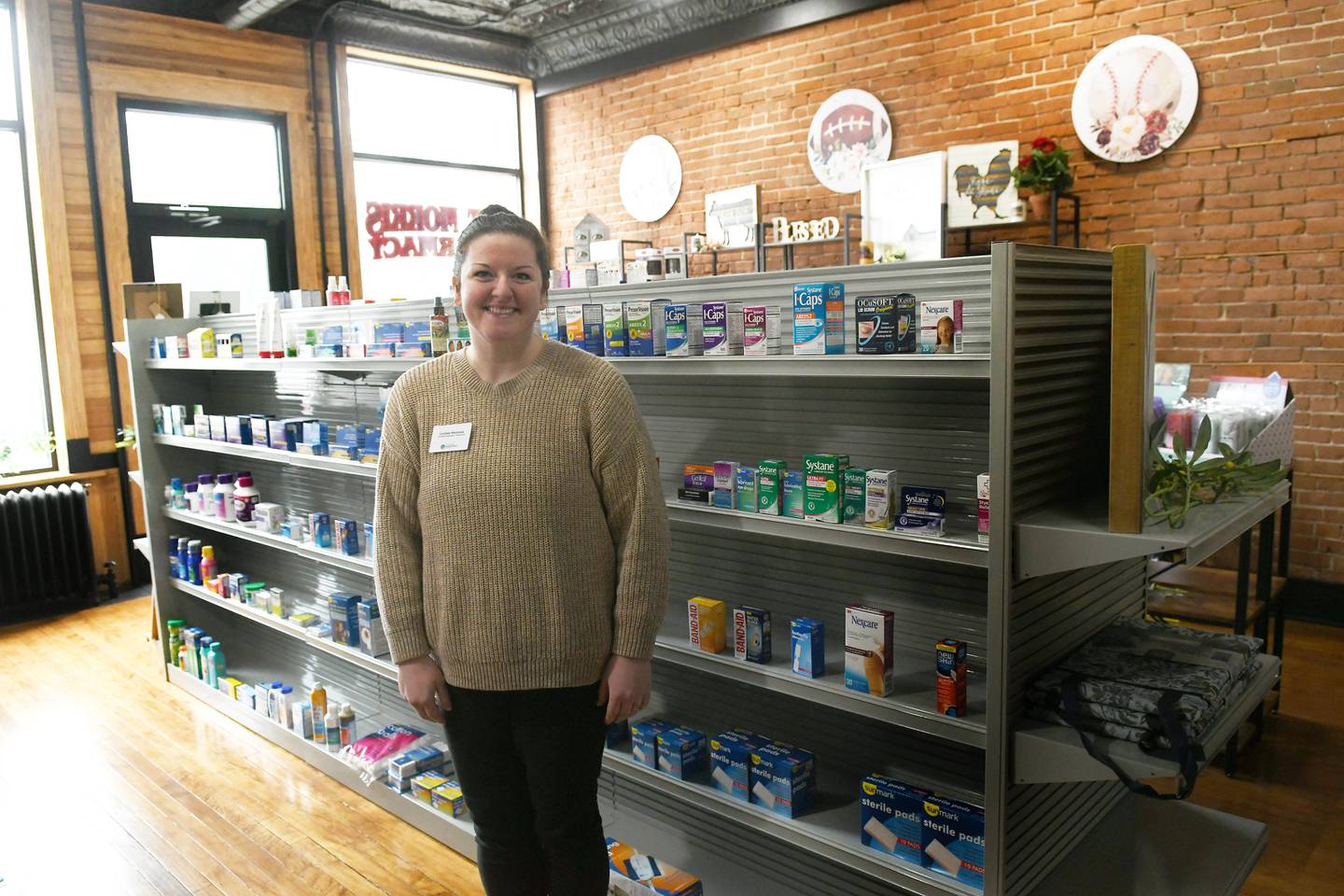 Lindsey Meinsma, a certified pharmacy technician, stands in one of the aisles at the new Mt. Morris Pharmacy which opened last week.