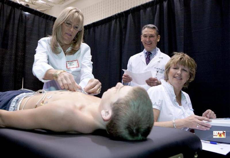 Cardiologist Dr. Mark Marek (back), founder of Young Hearts for Life, a program similar to Rhythm of Our Youth, conducts a cardiac screening.