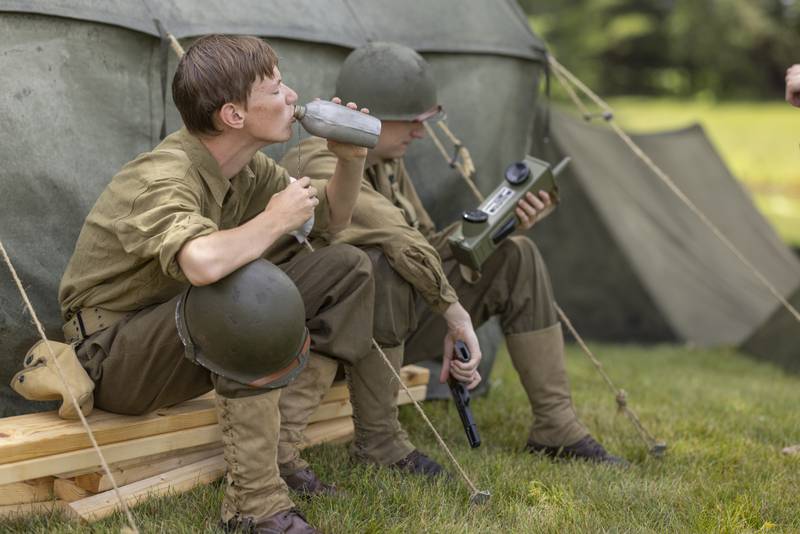 Reenactor Owen Phifer rehydrates back at base after the simulated battle Sunday, July 14, 2024, during the Ottawa Military Show in rural Ottawa.