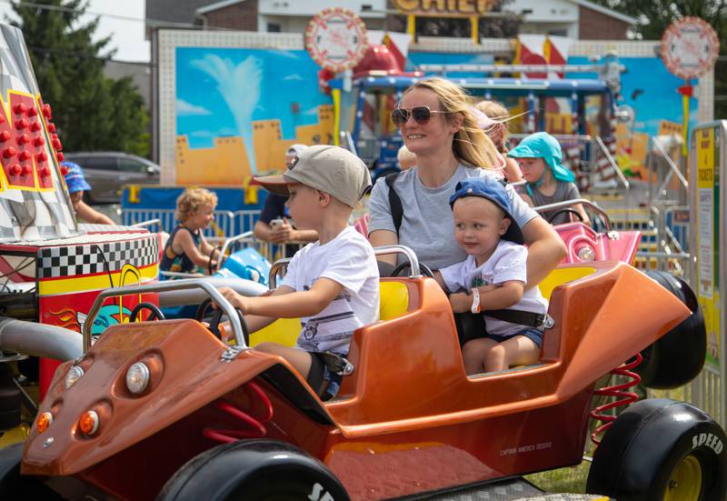 Anna, back, Lukas (5), left, and Nicholas (2)  Debski ride a carnival ride during the 75th anniversary of the McHenry County Fair in Woodstock on Wednesday, August 2, 2023.