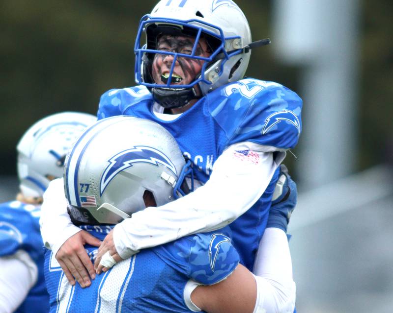 Woodstock’s Jackson Canty (22) howls in the arms of Bode Pedersen late in a win over Ottawa in varsity football at Larry Dale Field on the campus of Woodstock High School Saturday.