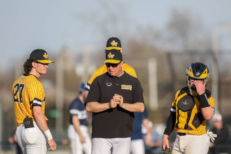Joliet West's head coach John Karczewski awaits the arrival of the relief pitcher during varsity baseball game between Oswego East at Joliet West.  April 10, 2023.