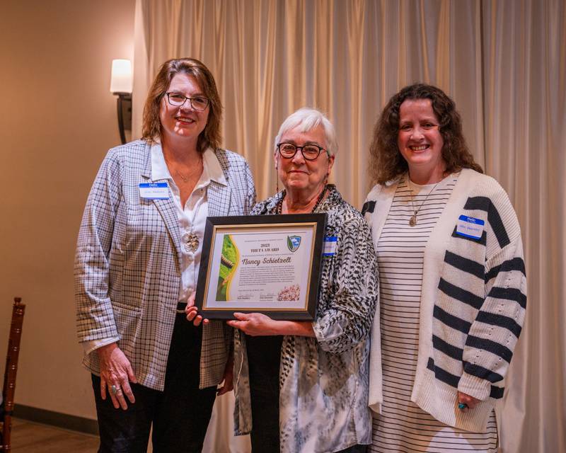 Defenders Board President Kim Hankins (L) and Defenders Executive Director Erin Kennedy (R) presented Nancy Schietzelt (M) with the Theta Award at the annual dinner on March 3, 2024