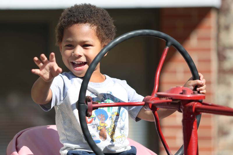 Xavier Seals, 4, from DeKalb waves to his mom from the seat of a vintage tractor Friday, Aug. 26, 2022, during Corn Fest in downtown DeKalb