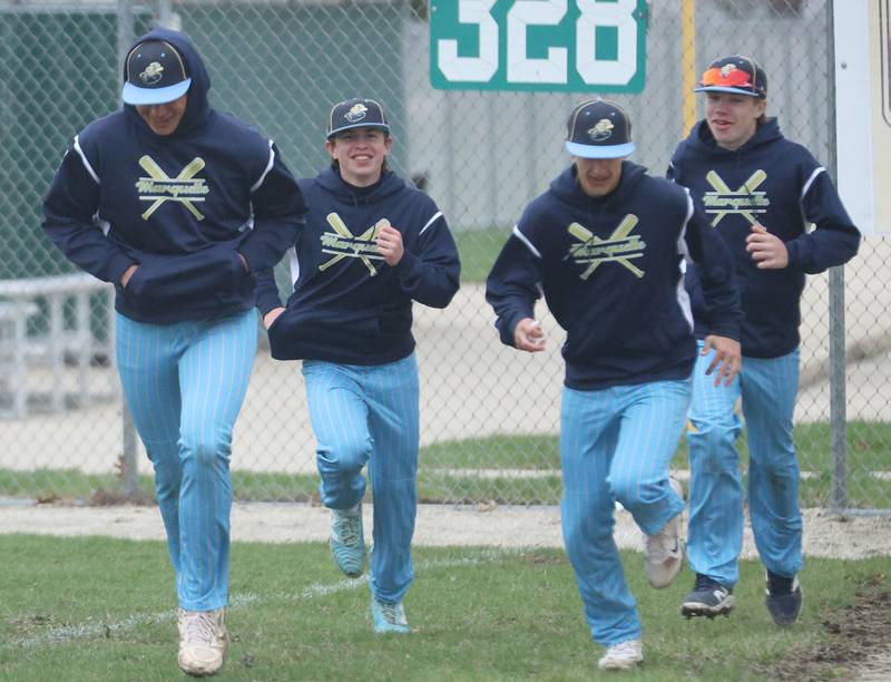 Marquette players run to the warning track to warm up in between innings while playing Eureka on Wednesday, April 1, 2026 at Masinelli Field in Ottawa.