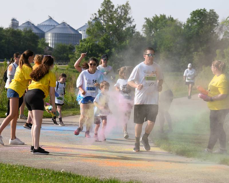 Participants get sprayed with color powder as they go through a color station on Saturday, June 7, 2025, during the CASA DeKalb County 5K Color Run held at the Sycamore Middle School.