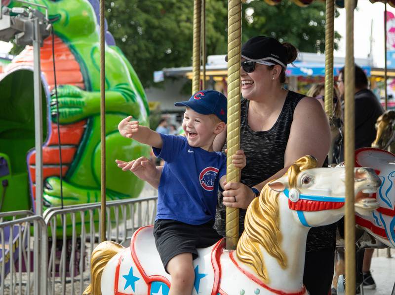 Kane, 4, (left) and Jessi (right) Fleming of Wheaton ride the carousel during the DuPage County Fair at the DuPage Event Center & Fairgrounds on Saturday, July 30, 2022.