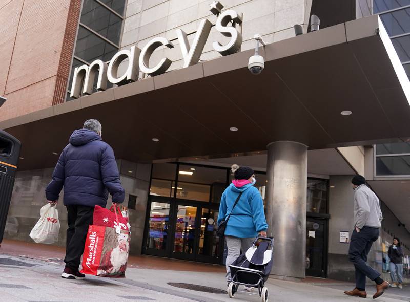 FILE - Shoppers walk to the Macy's store in the Downtown Crossing district, Wednesday, Nov. 17, 2021, in Boston.  Americans slowed their spending in November from October but  they  showed another month of resilience against higher prices and shortages in stores.   (AP Photo/Charles Krupa, File)