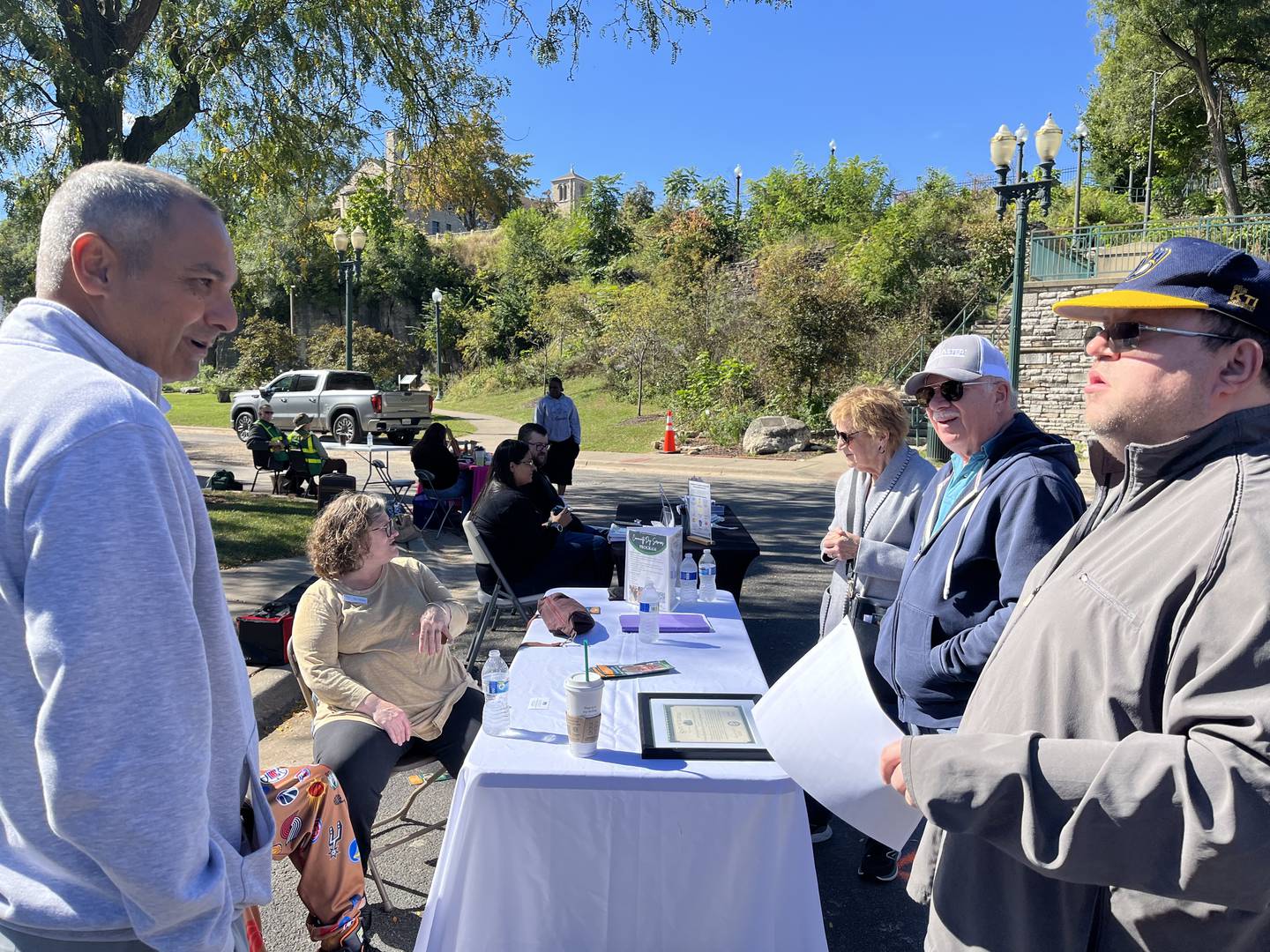 Brian Patel (left), executive director of United Cerebral Palsy Center for Disability Services in Joliet, speaks with attendees at the booth for the organization at Joliet's Disability Pride Fair on Saturday, Oct. 11, 2025.