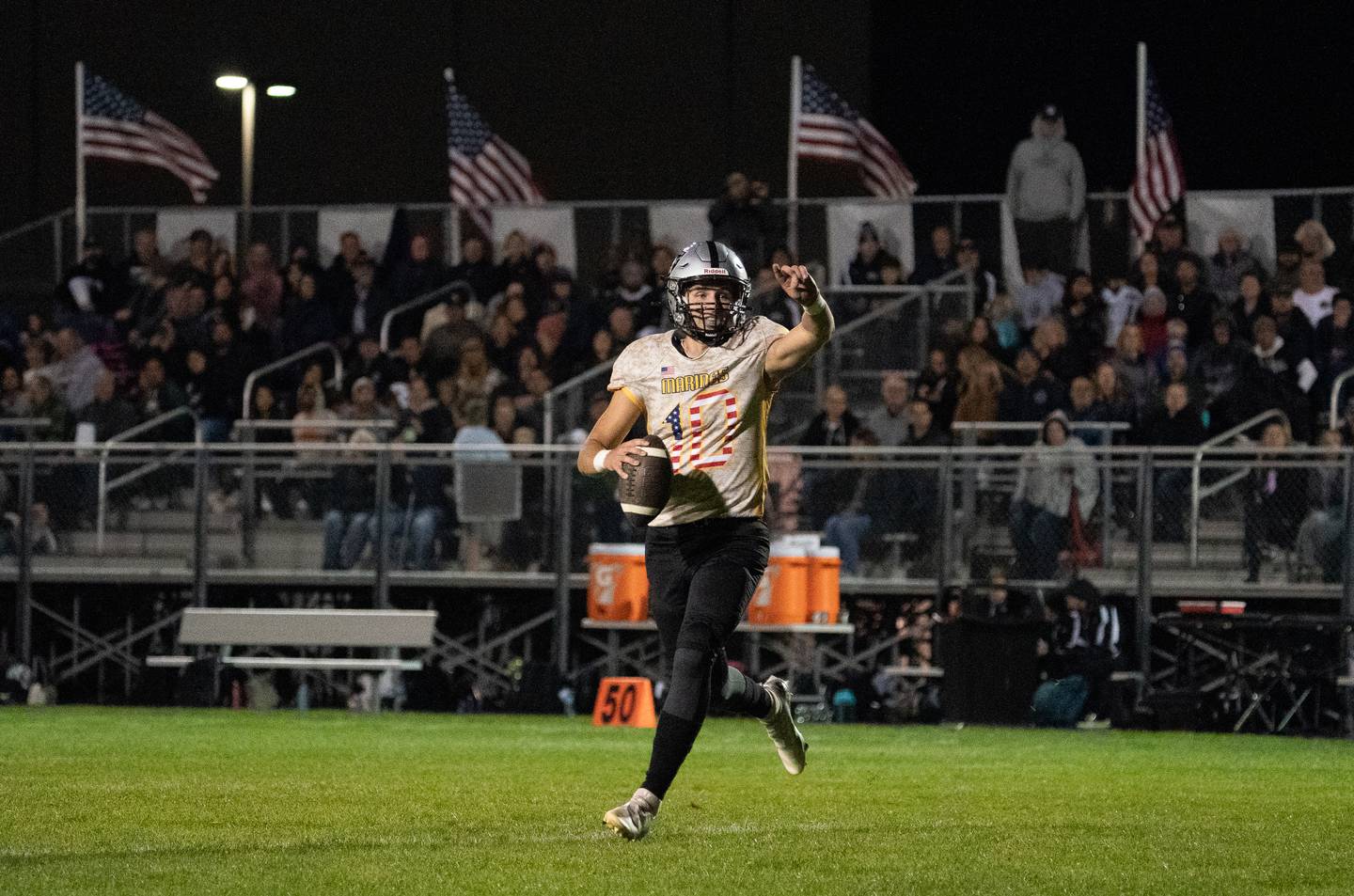 Kaneland’s Troyer Carlson (10) directs his offense while rolling out of the pocket against Sycamore during a football game at Kaneland High School in Maple Park on Friday, Sep 30, 2022.