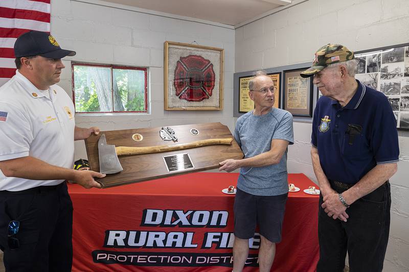 Dixon Rural Chief Dustin Dahlstrom (left) and board president Brian Mayer present John Foxley with the silver axe Saturday, May 16, 2026, honoring the retired firefighter for his 44 years of service. “He never missed a call day or night,” said Dahlstrom about Foxley’s dedication.
