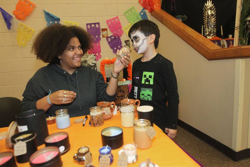 Regla LeMus, of Waukegan lets Morgan Bryant, 8, of Round Lake Beach smell the different scents in her Perfect Blend soy wax candles featured during the Day of the Dead Celebration at the Round Lake Beach Cultural & Civic Center.