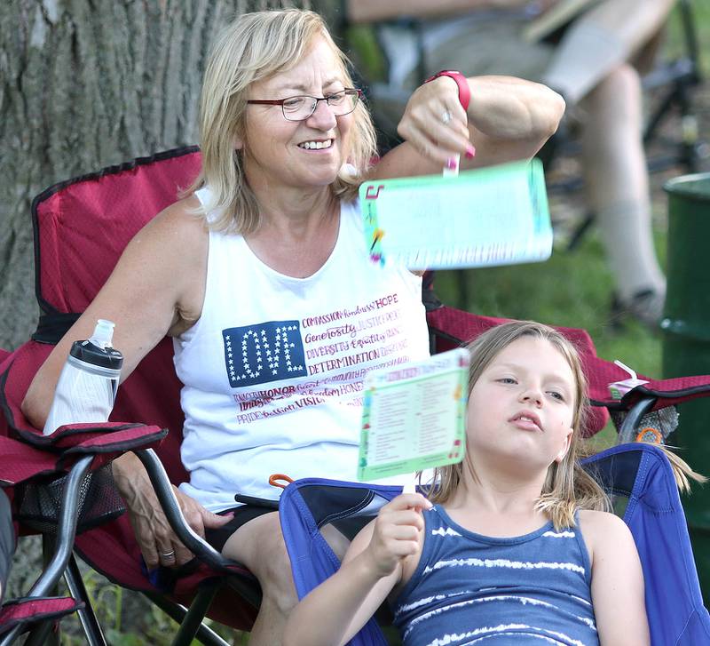 Maisie Schnorr, 6, from DeKalb, gets some help fanning from her grandma Wendy Schnorr, of Shabbona, as they try to stay cool in the 90 degree heat Tuesday, June 21, 2022, during the DeKalb Municipal Band concert at Hopkins Park in DeKalb. The band presents concerts at 7:30 p.m. during the summer every Tuesday through August 23, with the exception of July 5.