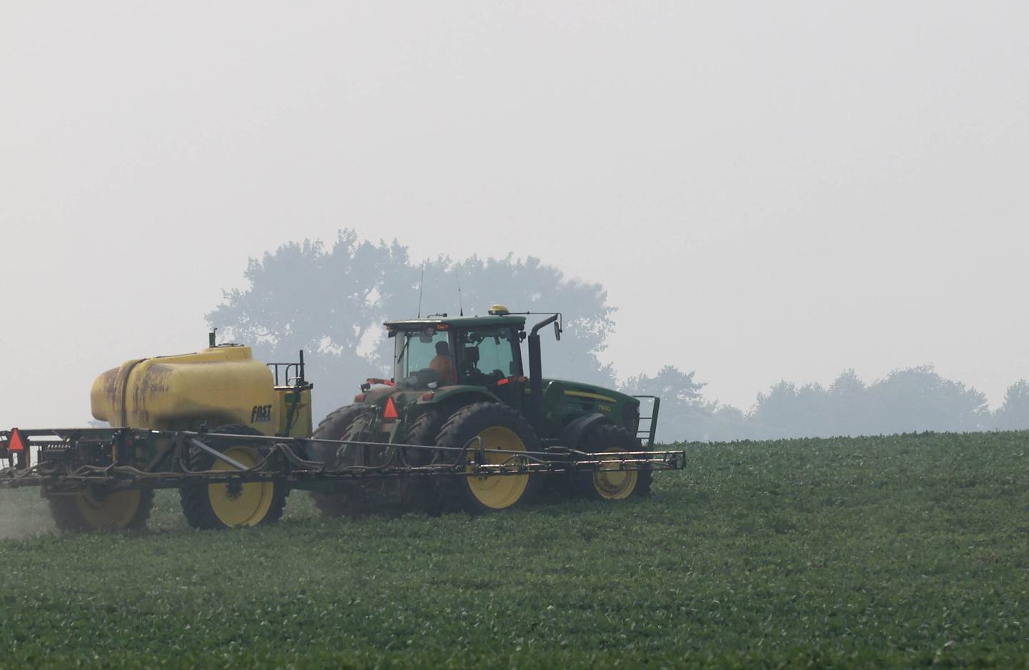 A farmer sprays his crops as he is partially shrouded by smoke from the Canadian wildfires Tuesday, June 27, 2023, in DeKalb. Haze from the fires in Canada has moved south into Illinois causing poor air quality that may be unhealthy especially to those with sensitive respiratory systems.