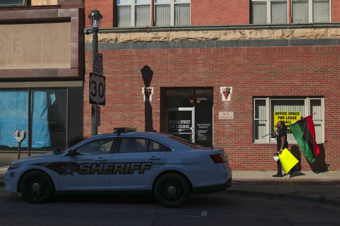 Joliet Black Lives Matter activist Karl Ferrell marches past a Will County Sheriff squad car on Friday, Sept. 17, 2021, outside of the District Attorney's Office in Joliet, Ill.