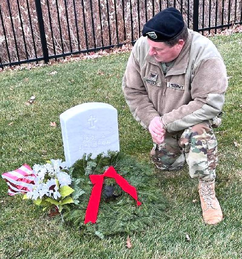 Retired Col. Paul J. Hettich of Antioch kneels near a grave at Fort Sheridan National Cemetery.